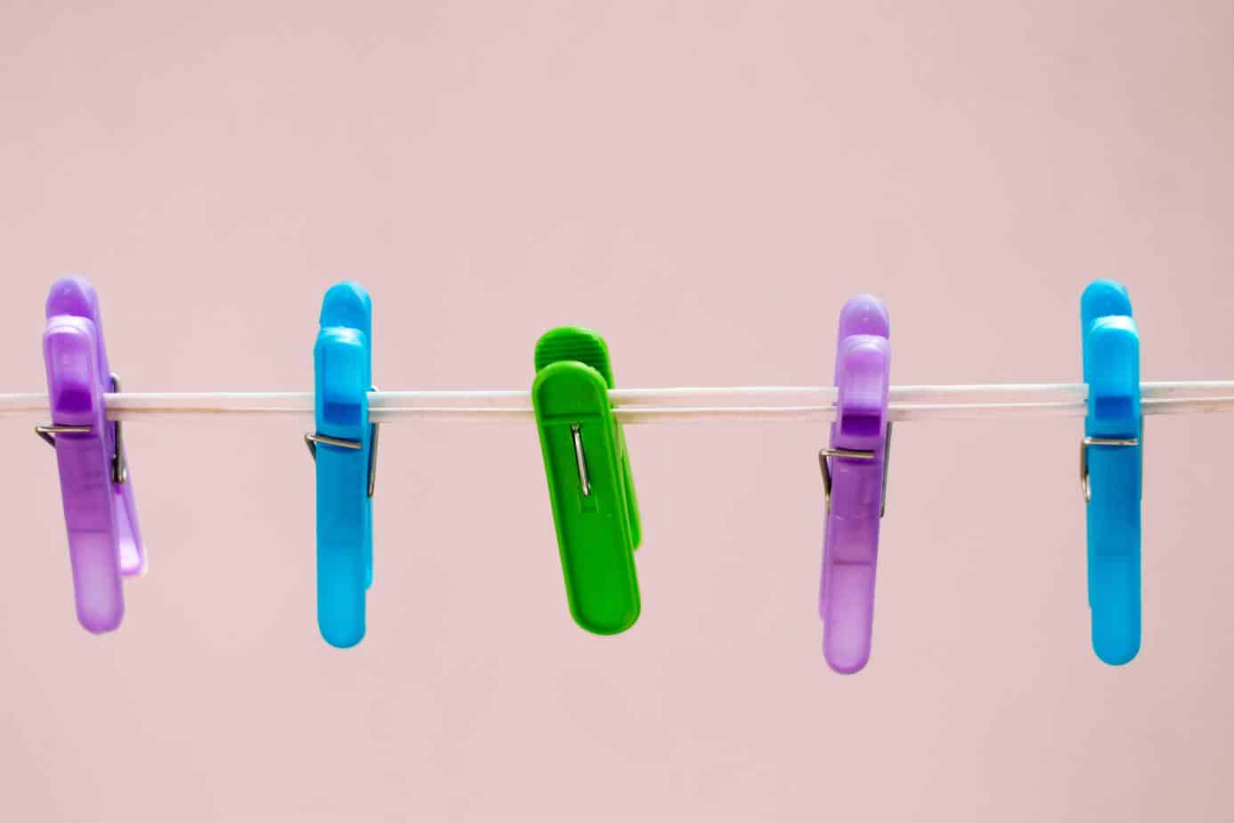 Clothes Line with different colored clips against pink background - frugal living tips