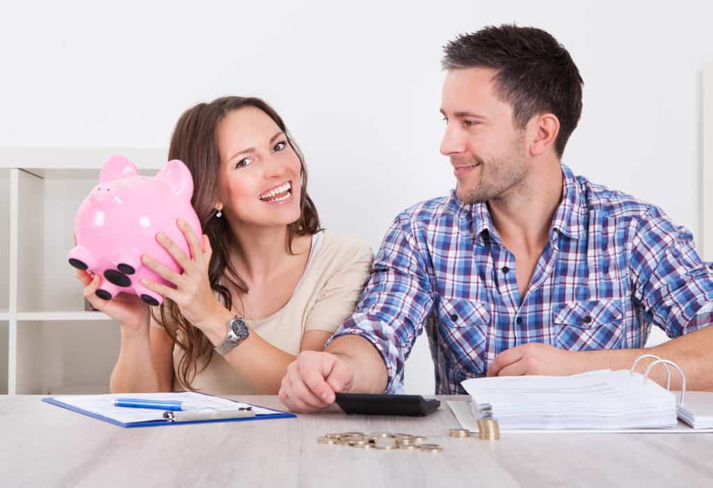 man and woman saving money and holding piggy bank - no spend challenge tips