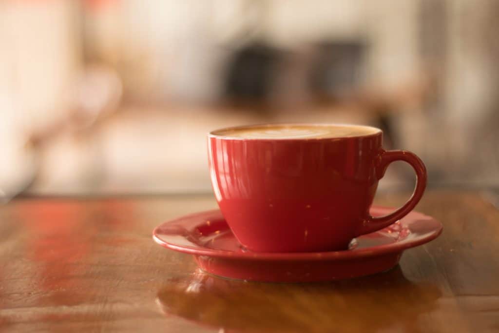 red cup of coffee on table - money saving tips for the kitchen