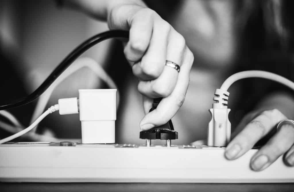woman unplugging plugs from electrical outlet - best money saving habits