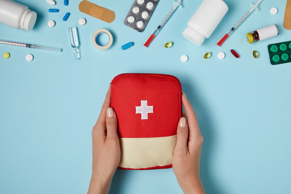 hands and first aid kit and supplies on a blue table
