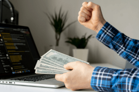 hand with money and laptop screen