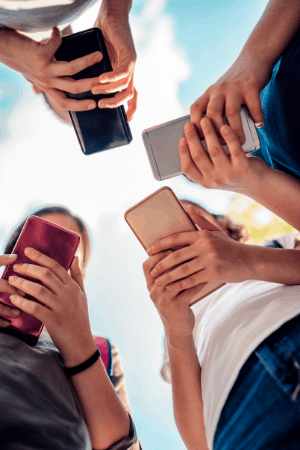 four people holding cell phones