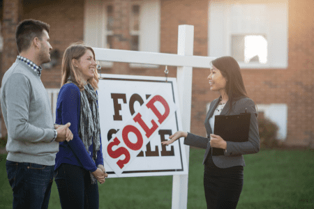 best way to flip money - couple with female real estate agent and sold sign