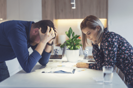 money flipping - angry man and woman at kitchen counter with bills