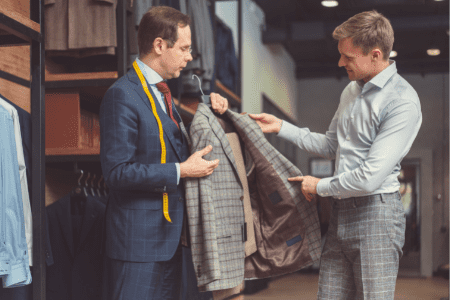 clothing alterations near me - male tailor showing gray plaid jacket to male client