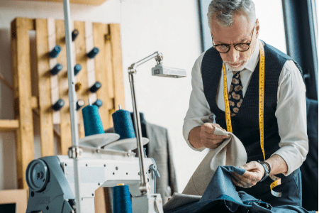 sharply dressed tailor looking at light and dark colored cloth