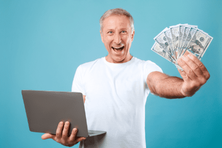 man holding laptop and cash