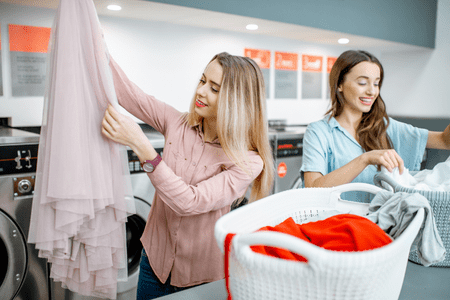 laundromats near me open - two smiling women folding laundry