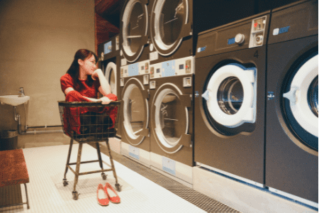 laundry near me - young woman sitting in laundry cart and smiling