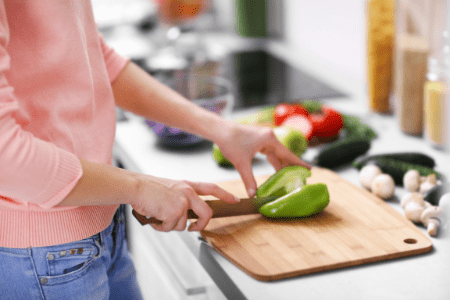 hands chopping up bell peppers to prepare a budget friendly chicken pasta casserole