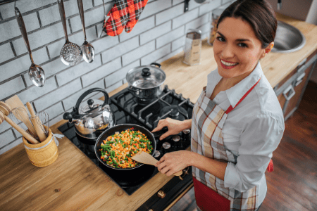 smiling woman in kitchen preparing a simple chicken pasta casserole