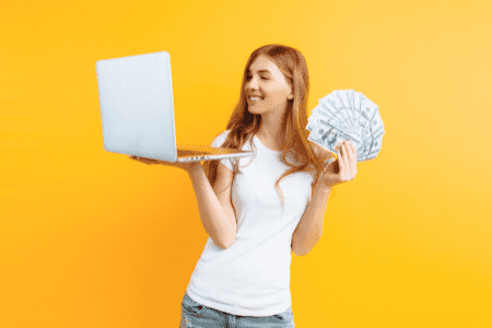 woman holding laptop and cash