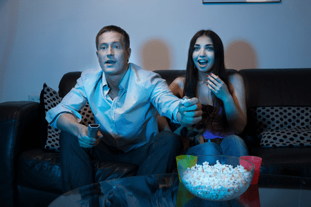 man and woman eat popcorn and make money watching Netflix