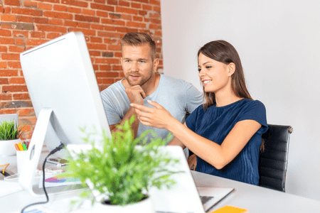 man and woman with computer discussing how to buy digital real estate