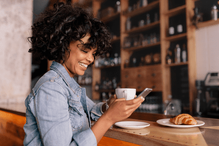 woman with phone smiling because of apps with instant sign on bonus