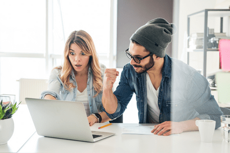 man and woman excited with laptop converting 64000 salary to hourly