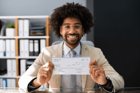 man holding paycheck and happy with 64K a year 