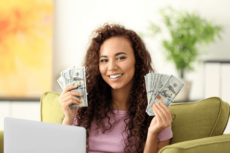 woman on laptop with cash