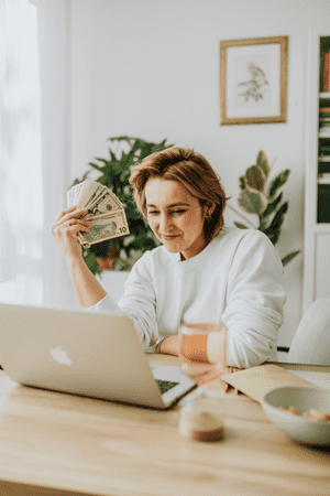 woman on laptop holding cash