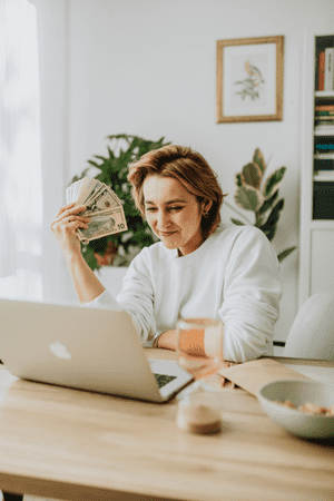 woman on laptop holding cash