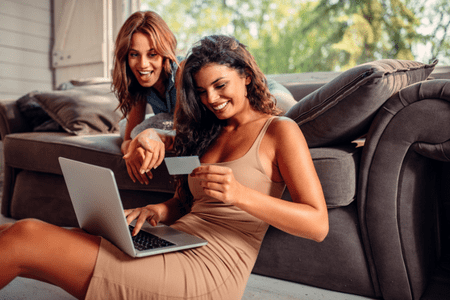 two happy women with laptop and $10 referral bonus