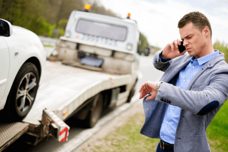 man looking at watch and tow truck