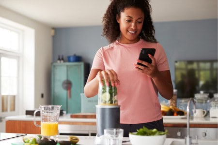 woman answering surveys on phone while in the kitchen