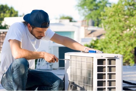 man servicing a heat pump