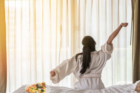woman with pizza slice in bed