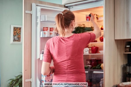 woman with packed food in container in fridge