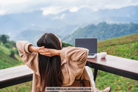 woman with laptop and coffee cup overlooking mountainside